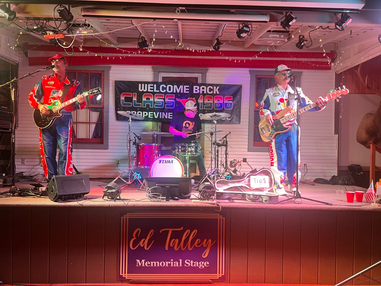 Ricky Bobby Music in race suits on stage at the Grapevine High School Class of 1986 reunion
